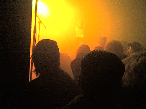Concert crowd silhouetted against a blazing orange stage light