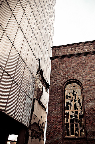 Brick factory wall with broken windows beside corrugated tower