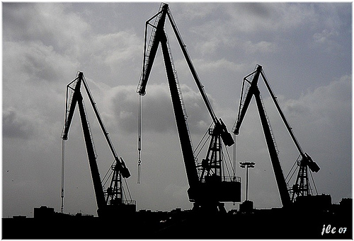 Harbor cranes silhouetted against a grey sky