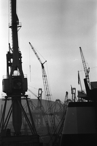 Dockyard cranes fading into fog, grainy film