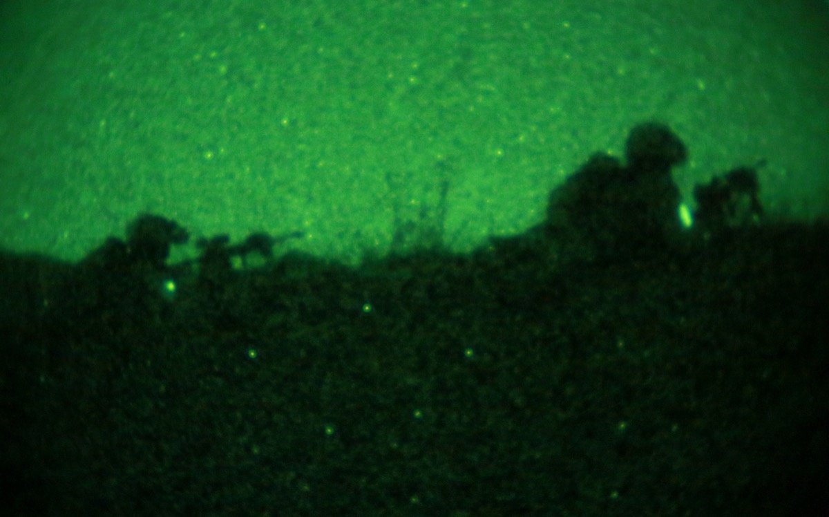 Green night-vision sky over silhouetted soldiers