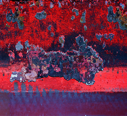 Red and black peeling paint, close up