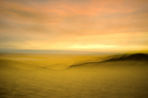 Yellow blurred dune landscape under a pale sky