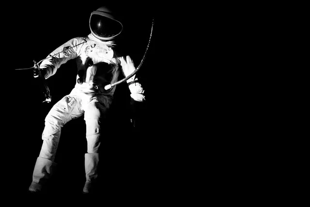 A white-suited astronaut suspended against a black background.