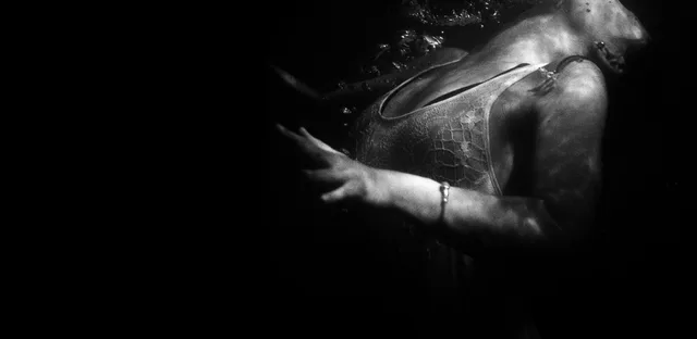A partially lit figure emerging from deep shadow.