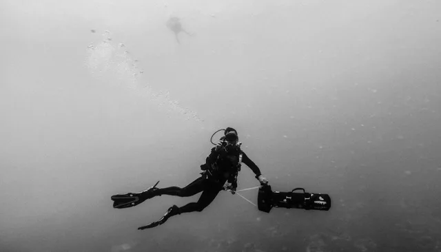 A diver suspended horizontally in open water.